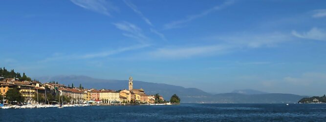 Trip Journey beliebte Urlaubsziele am Gardasee -  Mit einer Fläche von 370 km² ist der Gardasee der größte See Italiens. Es liegt am Fuße der Alpen und erstreckt sich über drei Staaten: Lombardei, Venetien und Trentino. Die maximale Tiefe des Sees beträgt 346 m, er hat eine längliche Form und sein nördliches Ende ist sehr schmal. Dort ist der See von den Bergen der Gruppo di Baldo umgeben. Du trittst aus deinem gemütlichen Hotelzimmer und es begrüßt dich die warme italienische Sonne. Du blickst auf den atemberaubenden Gardasee, der in zahlreichen Blautönen schimmert - von tiefem Dunkelblau bis zu funkelndem Türkis. Majestätische Berge umgeben dich, während die Brise sanft deine Haut streichelt und der Duft von blühenden Zitronenbäumen deine Nase kitzelt. Du schlenderst die malerischen, engen Gassen entlang, vorbei an farbenfrohen, blumengeschmückten Häusern. Vereinzelt unterbricht das fröhliche Lachen der Einheimischen die friedvolle Stille. Du fühlst dich wie in einem Traum, der nicht enden will. Jeder Schritt führt dich zu neuen Entdeckungen und Abenteuern. Du probierst die köstliche italienische Küche mit ihren frischen Zutaten und verführerischen Aromen. Die Sonne geht langsam unter und taucht den Himmel in ein leuchtendes Orange-rot - ein spektakulärer Anblick.